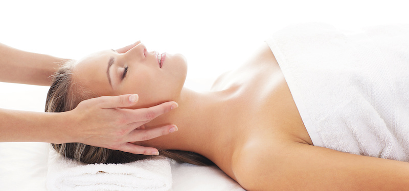 Woman laying on massage bed getting a relaxing face massage